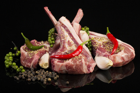 Raw lamb chops with spices and herbs isolated on black backgroundの写真素材