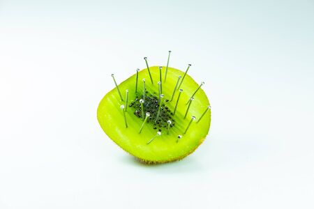Kiwi with needle on whiteの写真素材