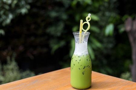 Cool green milk in a glass bottle on a wooden table.の写真素材