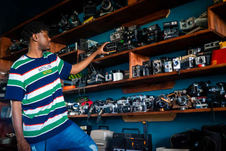 Models posing with vintage and modern cameras in front of shelves stocked with every camera manufactured for a concept shootのeditorial素材