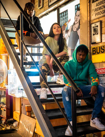 Models posing street wear clothing while sitting on the stairs inside a creative studio