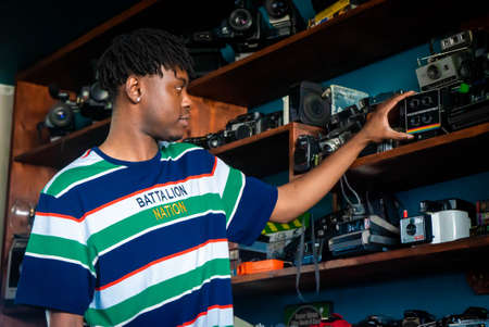 Models posing with vintage and modern cameras in front of shelves stocked with every camera...