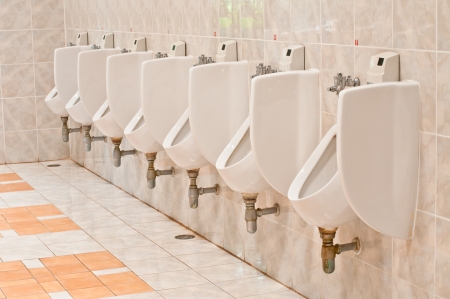 line of white porcelain urinals in public toilets の写真素材