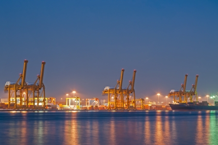 Container Cargo freight ship with working crane bridge in shipyard at dusk for Logistic Import Export background の写真素材