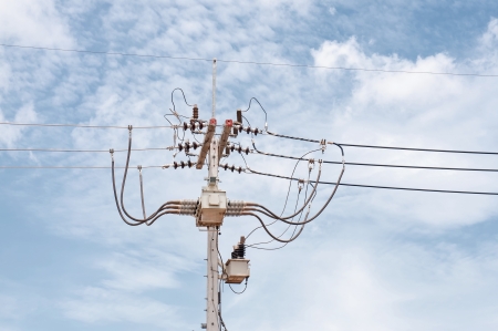 Energy and technology: electrical post by the road with power line cables, transformers against...