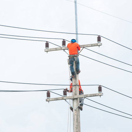 Electrician lineman repairman worker at climbing work on electric post power pole.