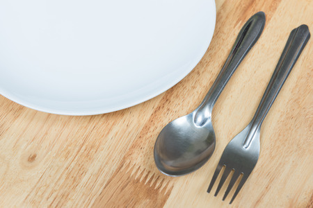 plate with spoon and fork on wooden tableの写真素材