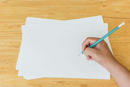 writing hand of student on blank paper with wood backgroundの写真素材