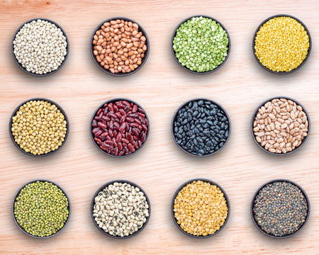 Mixed beans and lentils in bowl on wooden background.