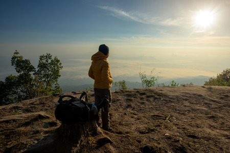 Man on the top of a rock to face the sunset - success concept