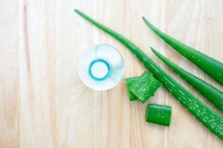 Fresh aloe vera leaves with aloe vera juice in bottle on wooden backgroundの写真素材