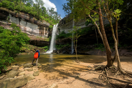 Man standing on the rock and looking at waterfall, Thailandの写真素材