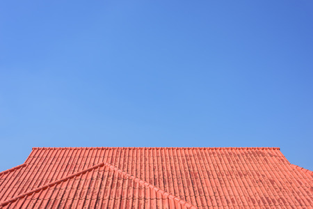 Red roof house with tiled roof on blue sky.の写真素材