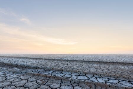 Soil drought cracked landscape on sunset sky