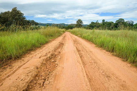 View of dirt road in countryside with blue skyの写真素材