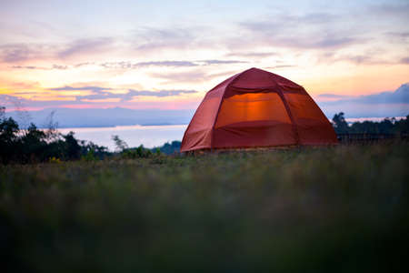 Illuminated orange Camping tent at sunrise.の写真素材