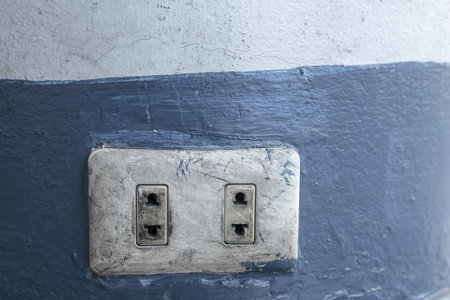 Old electrical power socket plug outlet on concrete wall.
