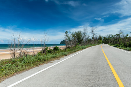 Side view of asphalt road with beach on sea and beautiful blue sky.の写真素材