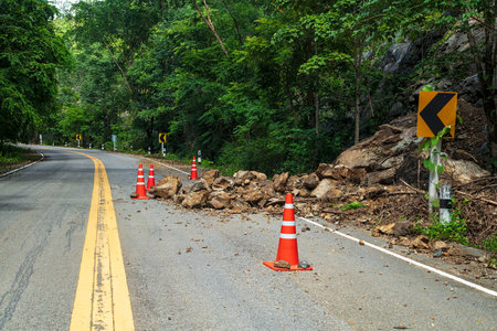 Rocks fell from the mountains onto the road, destroying the asphalt and blocking half of the roadway.の写真素材