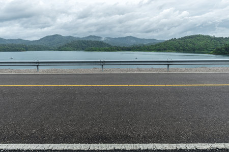 Side view of asphalt road with the lake and beautiful mountains. Road in rainy season. road background.の写真素材