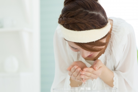 Beautiful asian woman washing her face with clean waterの写真素材