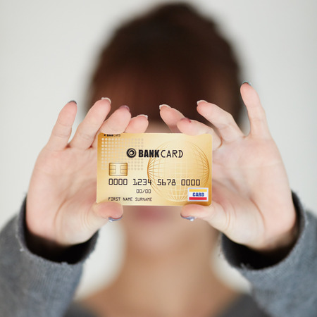 A beautiful woman holds out a business or credit cardの写真素材