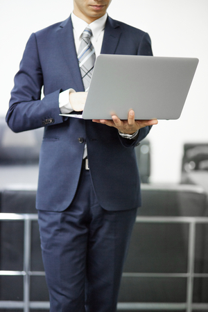 Young businessman with laptop in officeの写真素材