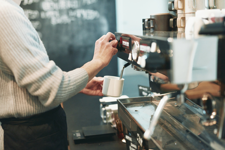 Portrait of a young man standing at the counter of his cafeの写真素材