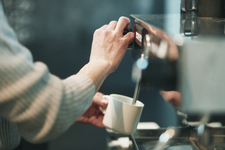 Portrait of a young man standing at the counter of his cafeの写真素材