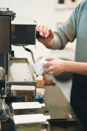 Portrait of a young man standing at the counter of his cafeの写真素材