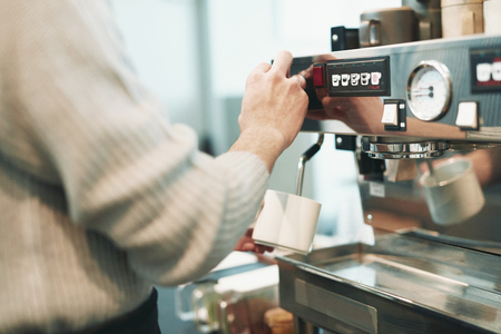 Portrait of a young man standing at the counter of his cafeの写真素材