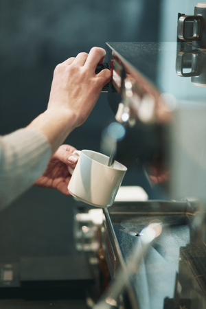 Portrait of a young man standing at the counter of his cafeの写真素材