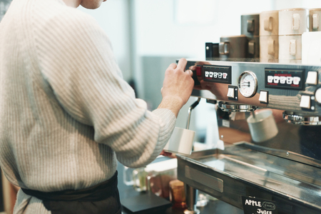 Portrait of a young man standing at the counter of his cafeの写真素材