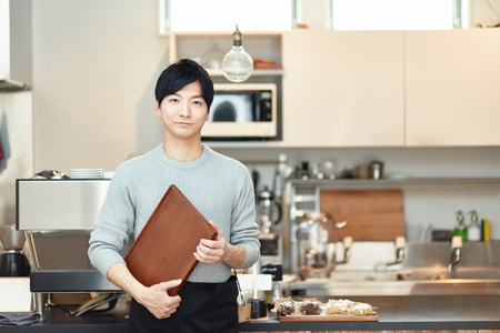 Portrait of a young man standing at the counter of coffee shopの写真素材