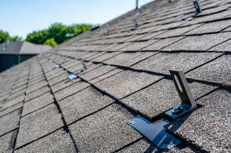 Residential asphalt shingle roof with metal anchors installed for the installation of a solar panel rail and racking systemの写真素材