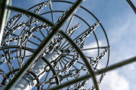 Underneath a disc golf goal looking up with selective focus on the chain basket.