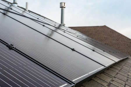 Selective focus on solar panels installed on a residential asphalt shingle roof