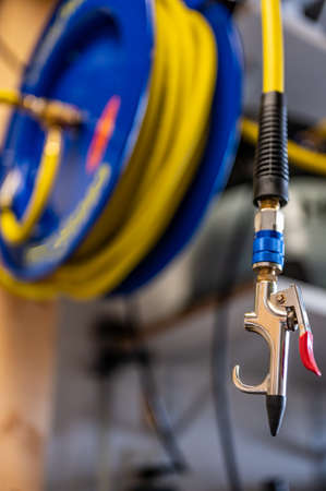 auto-rewinding air hose reel with coiled tubing mounted on a wall in a shopの写真素材