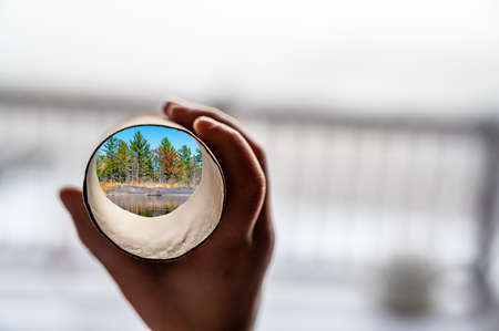 Child holding a cardboard toilet paper tube as a telescope to see through to imagine another world