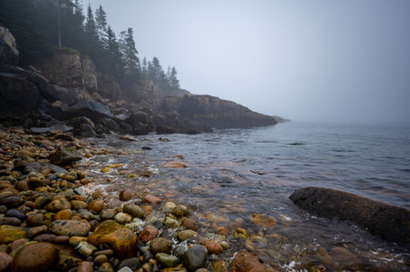 Multi-colored round rocks on Little Hunters Beach in Acadia National Park, Maine. Tide coming in as waves crash.の写真素材