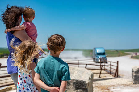 Mother and children looking into the distance while a semi truck comes up the roadの写真素材