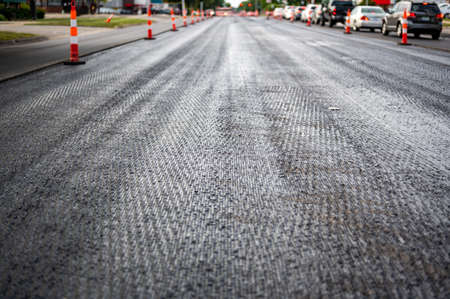 Low angle shot across a scarified street under construction with lanes on either side blocked off.の写真素材