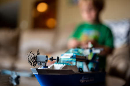 Tiffin, Iowa, USA - 9.2021 - Focus on Lego ship construction set with blurred child in the background playingのeditorial素材