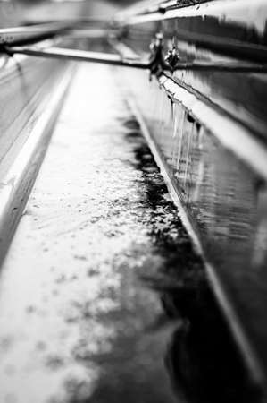Selective focus on a section of residential guttering with hanger conveying water during a storm. Rain splatters and drops visible.の写真素材