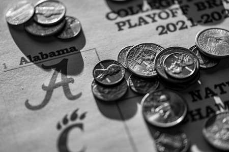 Tiffin, Iowa, USA - 12.2022 - Selective focus on 2021-2022 College Football Playoff Bracket with scattered coins.のeditorial素材