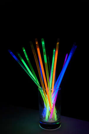 arrangement of multi-colored glow sticks against a black backgroundの写真素材