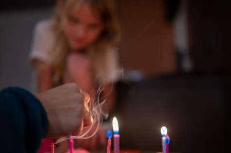 Selective focus on lighting candles on a birthday cake with a blurred child watching in the backgroundの写真素材