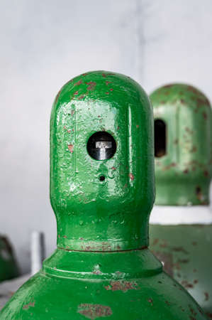 Compressed gas cylinders being stored vertically secured by a metal chain and a metal cap.の写真素材