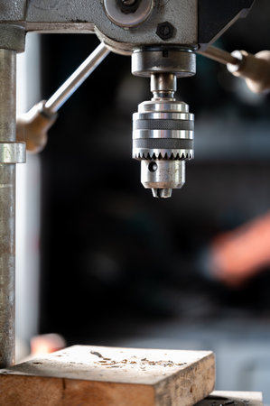 Industrial drill press with wooden board underneath.の写真素材