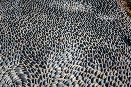 Selective focus on decorative pattern of river rocks laid in garden footpath.